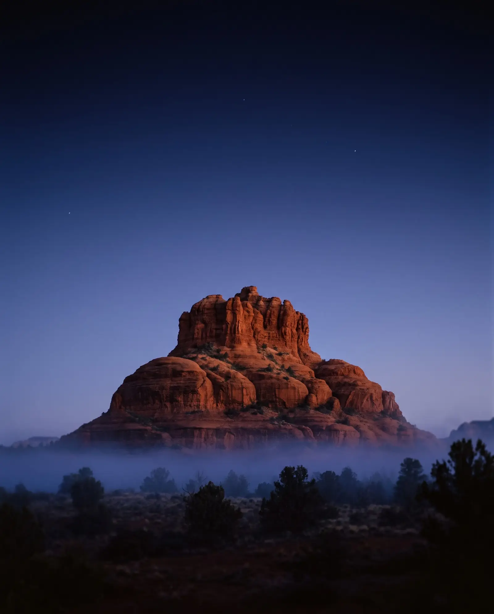 Formación de roca roja de Sedona al anochecer, bajo un cielo índigo con las primeras estrellas