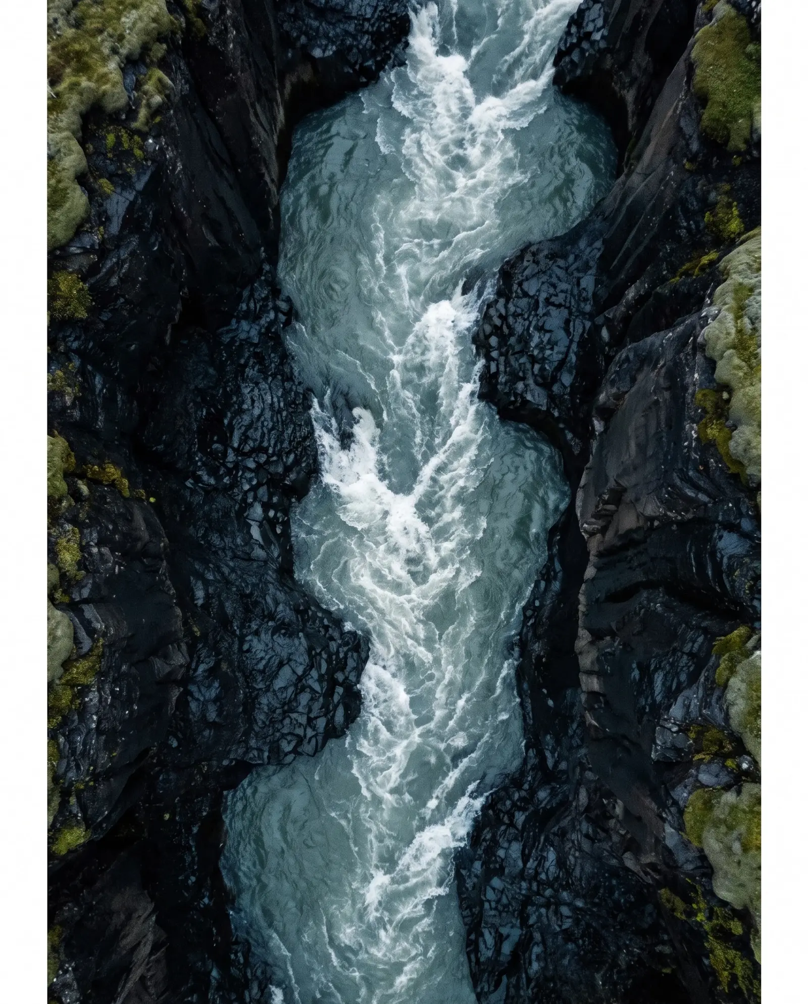 Río glaciar rugiendo entre paredes de basalto negro, visto desde lo alto