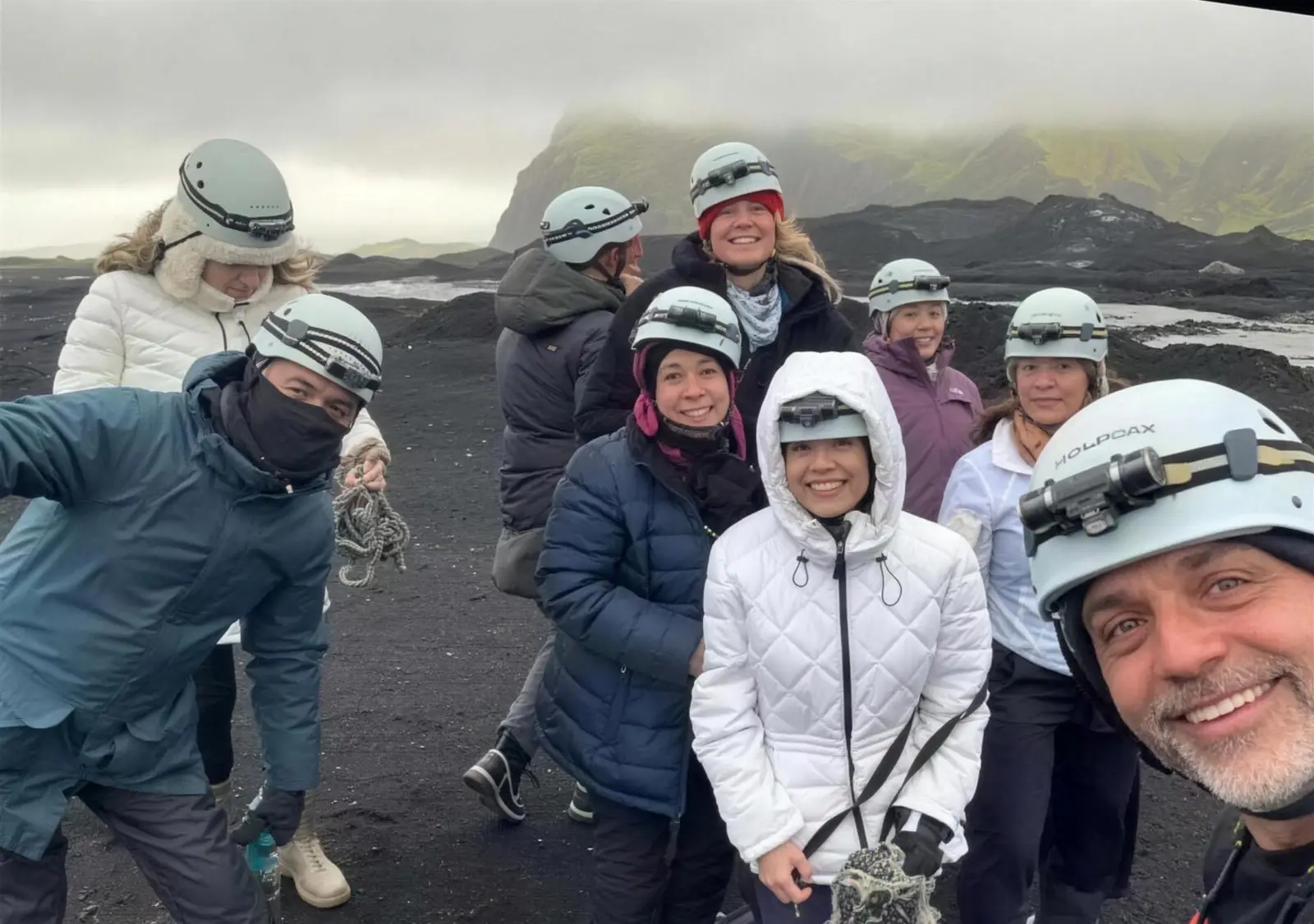 Grupo de viajeros con cascos en un campo de lava de arena negra