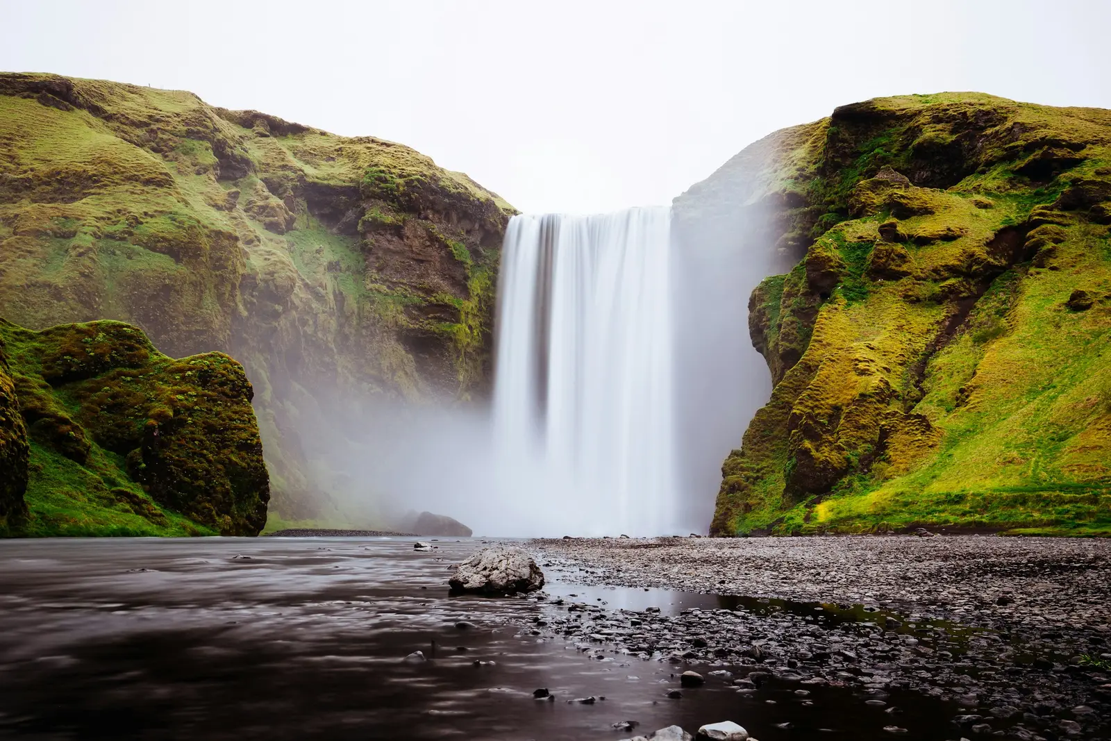 Cascada islandesa cayendo con fuerza entre acantilados verdes